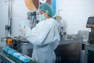 Workers producing surgical mask in modern factory, Covid-19 protection and medical concept.