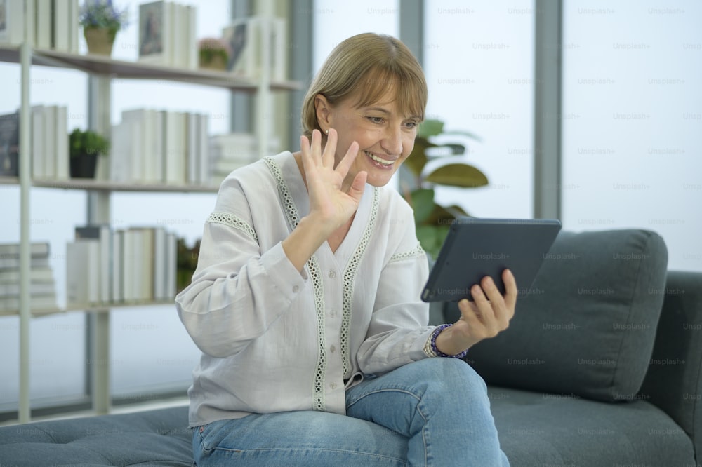 A happy Caucasian senior woman video call to family or friends, relax at home, smiling healthy senior retired grandparents, older grandparent technology concept