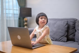 Una chica asiática feliz que usa una computadora portátil para estudiar en línea a través de Internet en casa. Concepto de e-learning