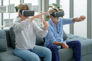 Una pareja de ancianos caucásicos que usa una caja de realidad virtual en casa