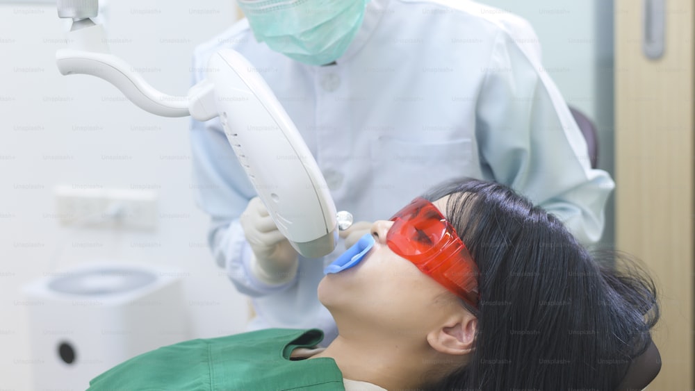 A woman wearing protective glasses  examining by stomatologist , Tooth whitening by ultraviolet lamp