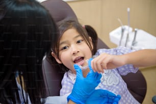 Una dentista que muestra invisalign a una niña en una clínica dental, chequeo de dientes y concepto de dientes sanos
