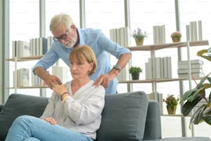 Homme caucasien âgé faisant un massage pour sa femme dans le salon