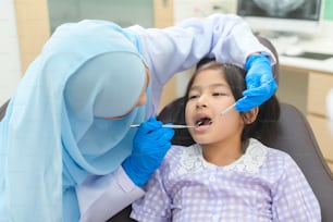 치과 진료소에서 무슬림 치과 의사가 치아를 검사한 귀여운 소녀, 치아 검진 및 건강한 치아 개념
