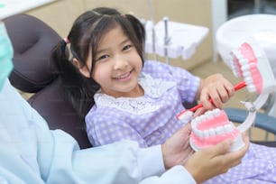 Une petite fille mignonne ayant des dents examinées par un dentiste dans une clinique dentaire, un contrôle des dents et un concept de dents saines