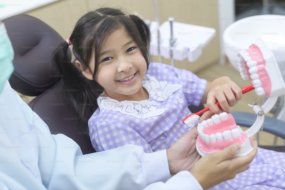Una niña linda que tiene dientes examinados por el dentista en la clínica dental, chequeo de dientes y concepto de dientes sanos