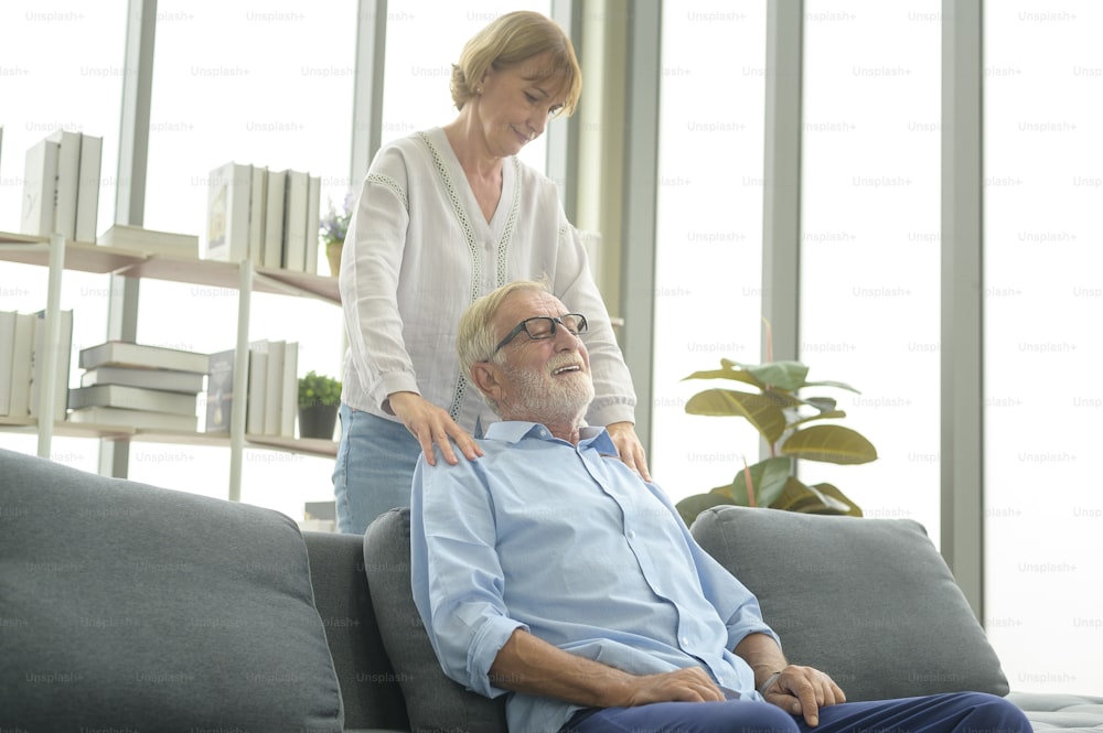 Hombre caucásico mayor haciendo masaje para su esposa en la sala de estar