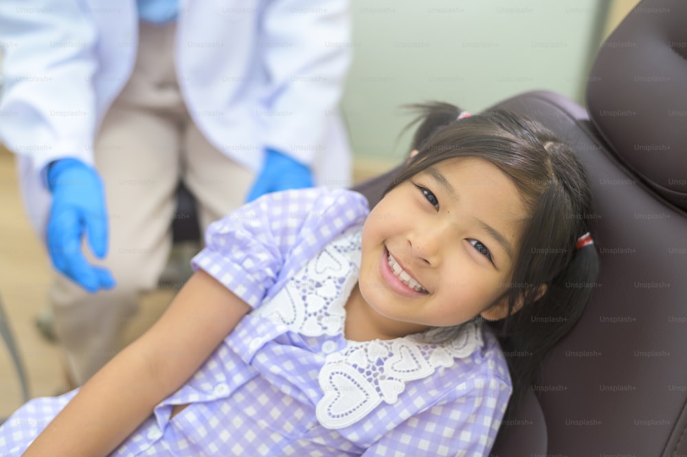Une petite fille mignonne ayant des dents examinées par un dentiste dans une clinique dentaire, un contrôle des dents et un concept de dents saines