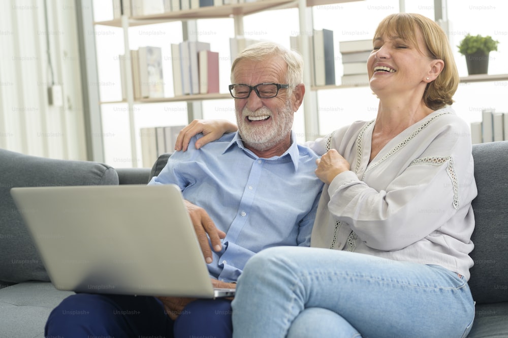 Felice coppia di anziani caucasici che usano il computer portatile a casa