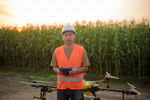 Ein männlicher Ingenieur, der Drohnen steuert, die Dünger und Pestizide über Ackerland sprüht, High-Tech-Innovationen und intelligente Landwirtschaft