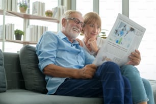 Coppia felice caucasica senior si sta rilassando, leggendo il giornale in soggiorno
