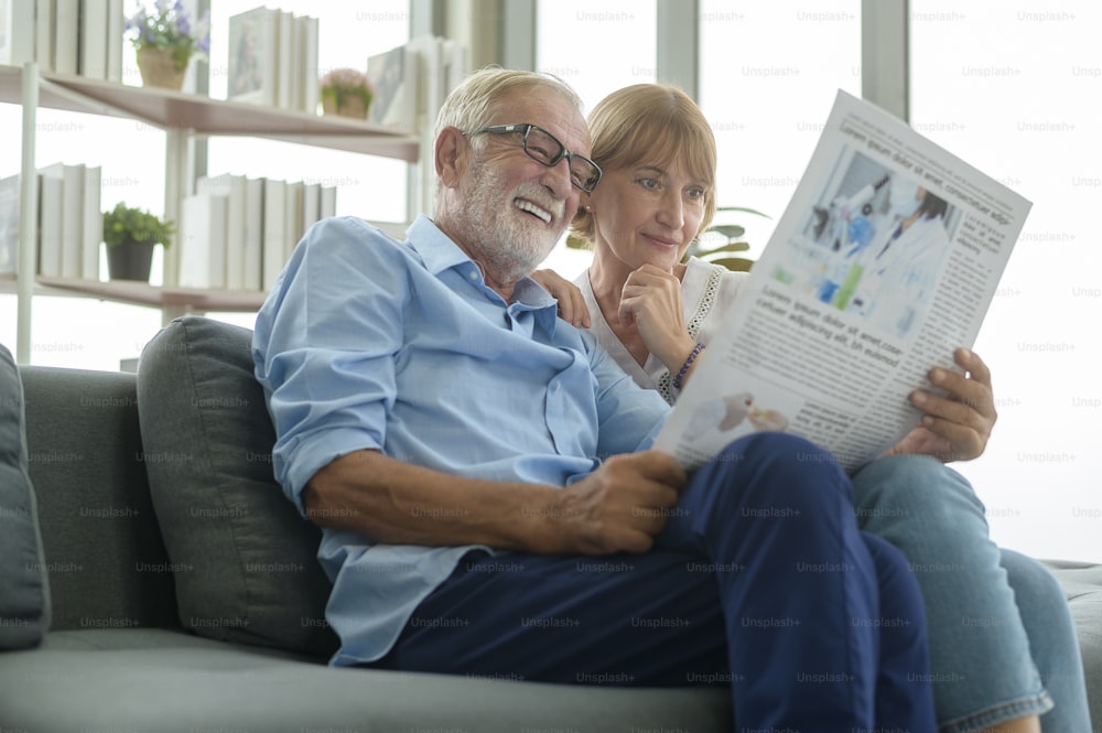 행복한 커플 백인 노인은 거실에서 신문을 읽고 휴식을 취하고 있습니다.