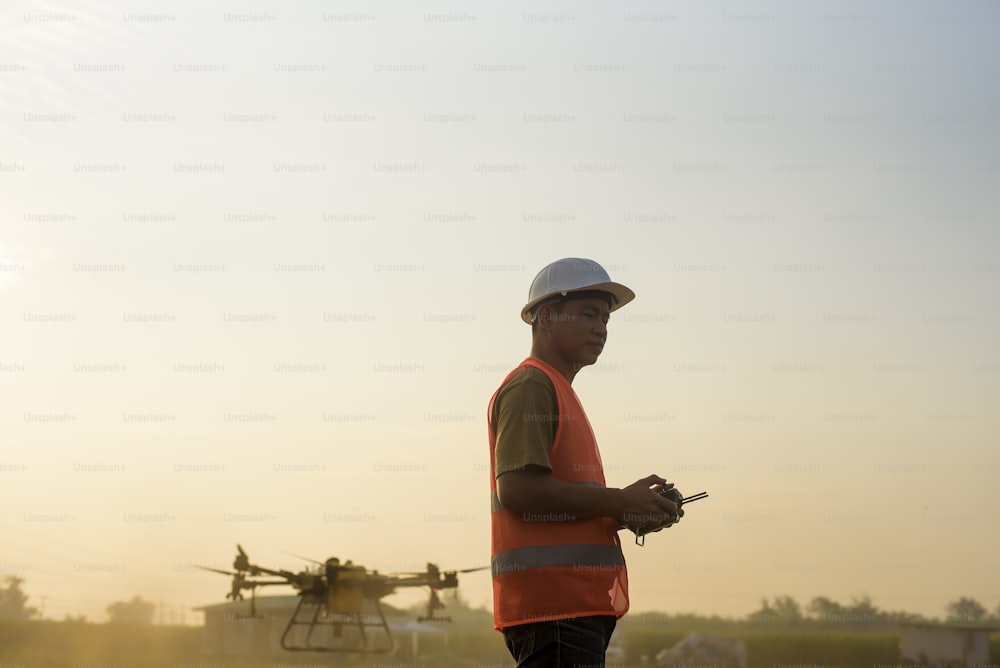 Un ingegnere maschio che controlla il drone che spruzza fertilizzanti e pesticidi su terreni agricoli, innovazioni ad alta tecnologia e agricoltura intelligente