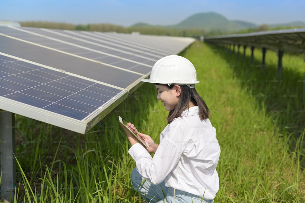 Uma engenheira usando capacete na Fazenda de Células Fotovoltaicas ou no Campo de Painéis Solares, eco friendly e energia limpa.
