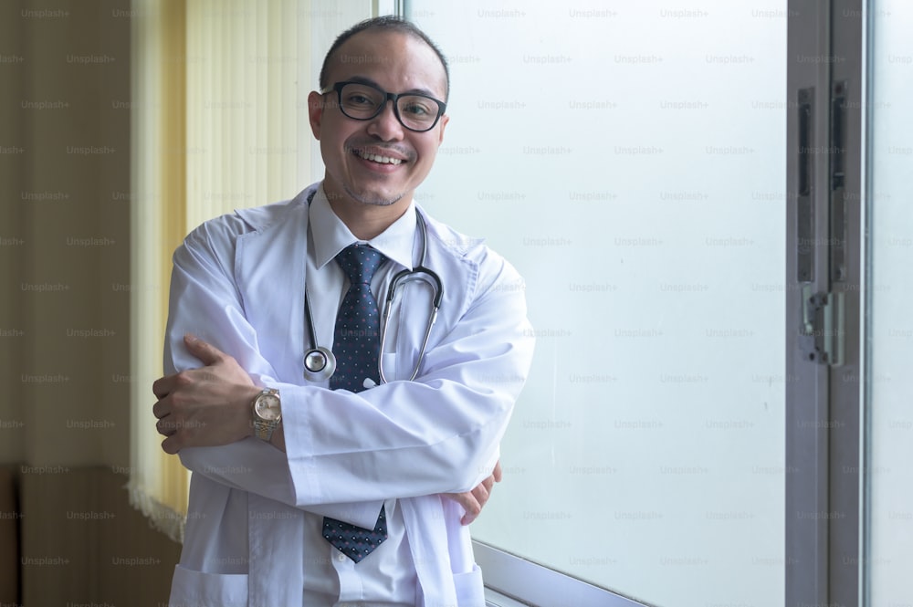 Retrato do médico sorridente confiante vestindo casaco branco no hospital