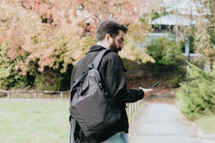 a man with a backpack looking at his cell phone