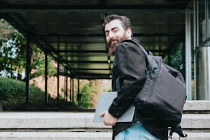 a man with a beard carrying a laptop