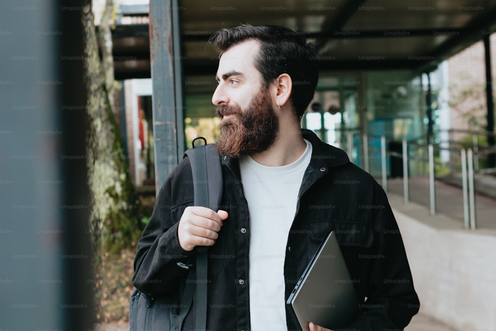 Un homme avec une barbe tenant un ordinateur portable