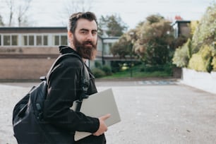 a man with a beard holding a laptop