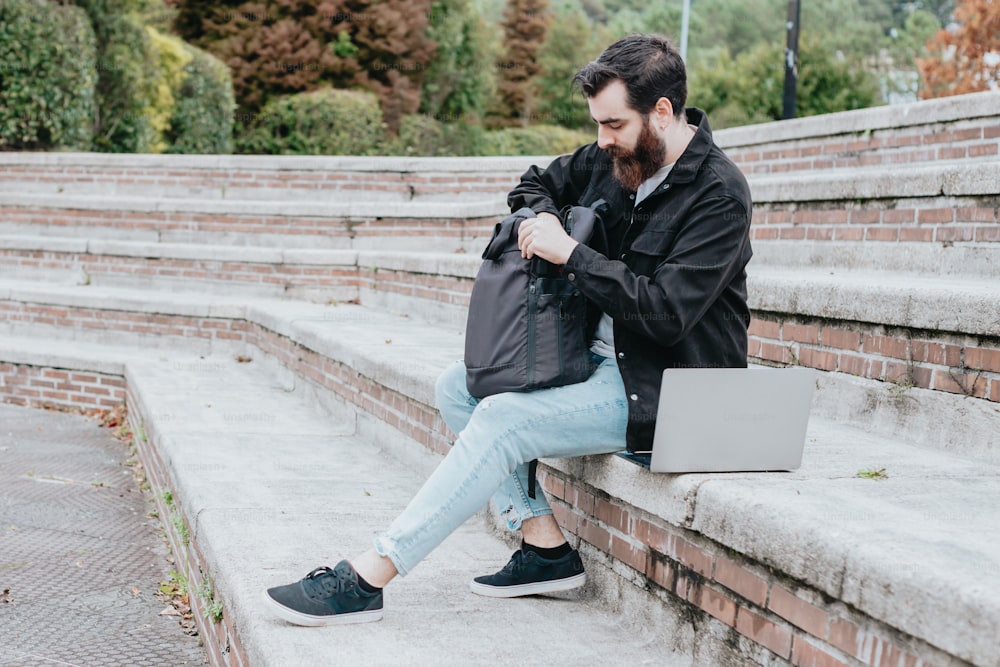 Un homme assis sur des marches avec un ordinateur portable sur ses genoux