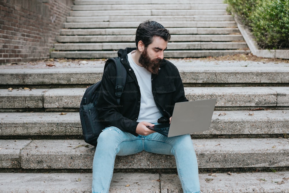 Un uomo seduto sui gradini usando un computer portatile