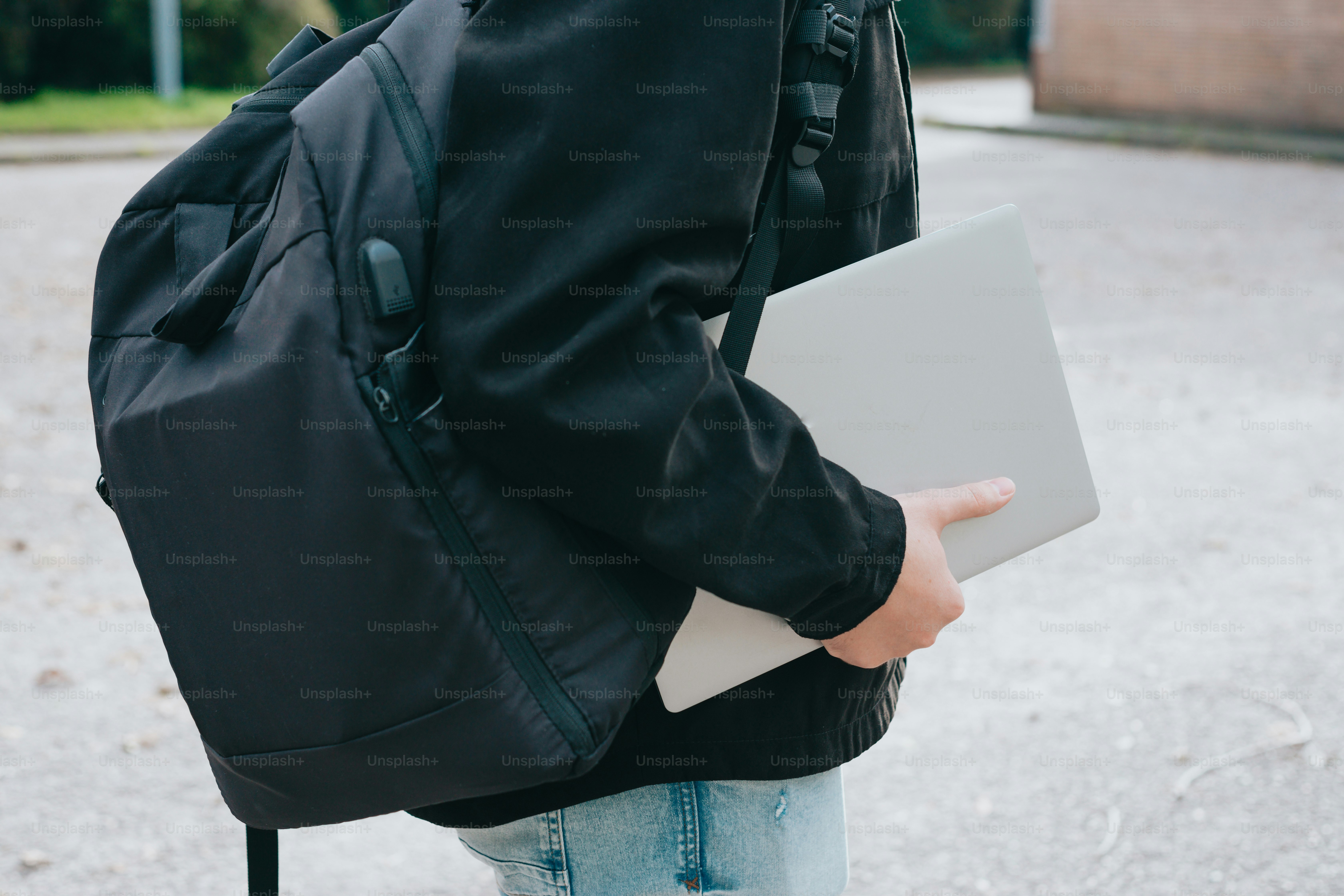 Una persona con una mochila sosteniendo una computadora portátil