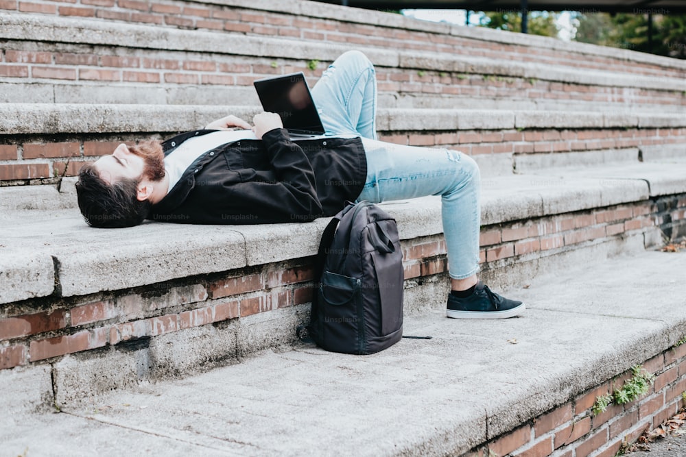 Un homme allongé sur les marches à l’aide d’un ordinateur portable