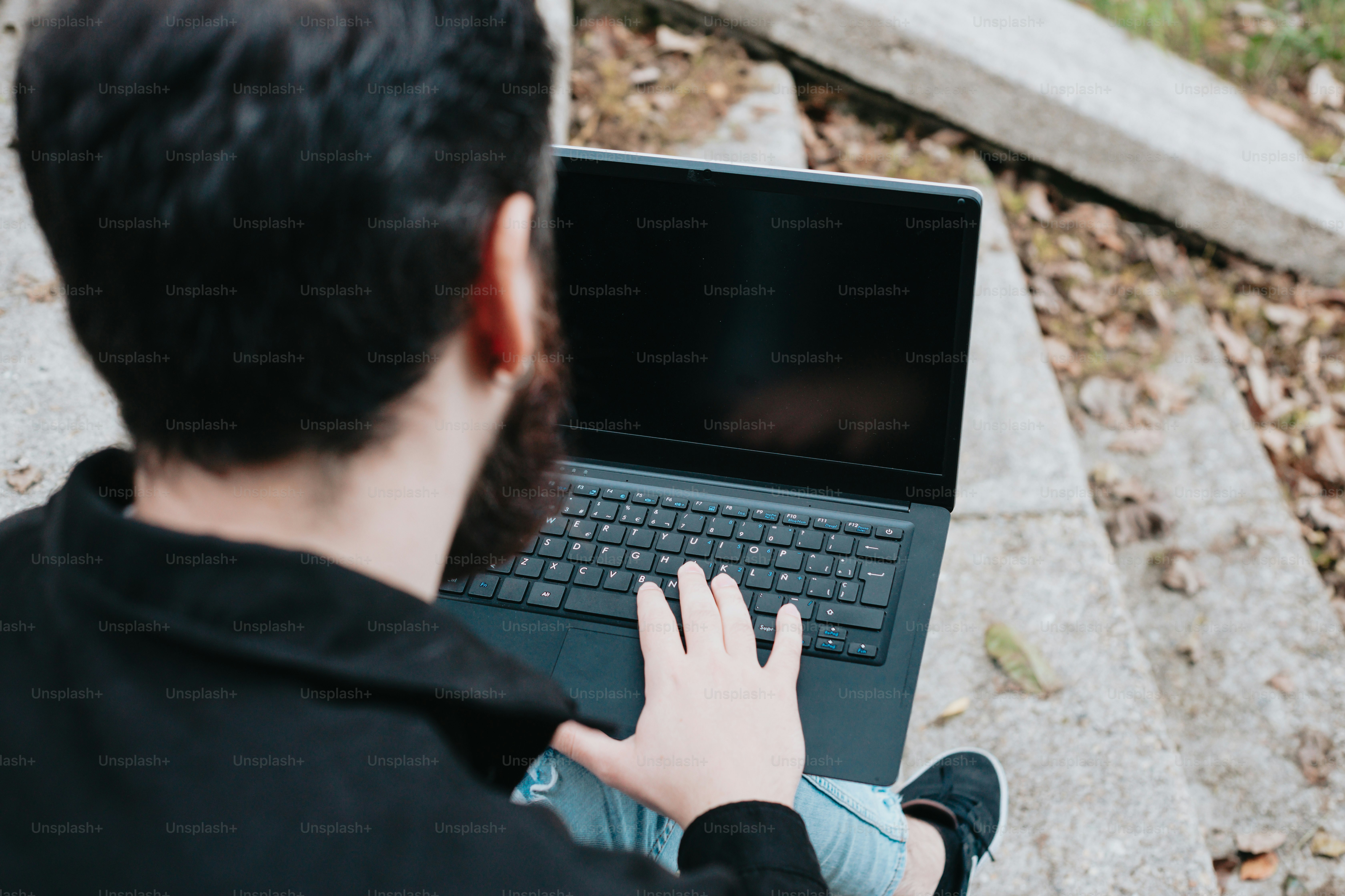 Un hombre sentado en el suelo usando una computadora portátil