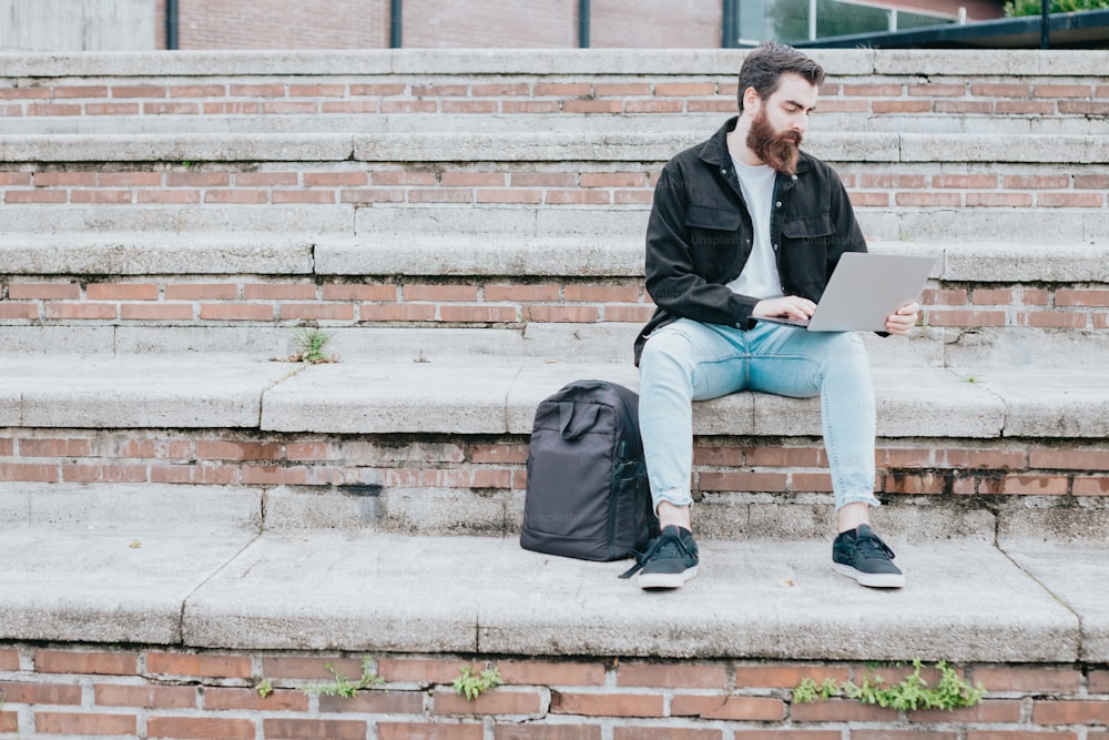 Un uomo seduto sui gradini usando un computer portatile