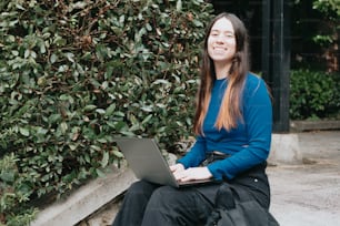 a woman sitting on the ground with a laptop