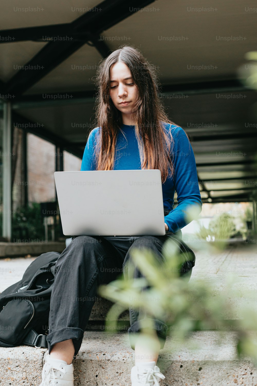 a woman sitting on a ledge with a laptop