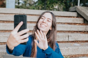 Una mujer sentada en los escalones tomando una foto con su teléfono celular
