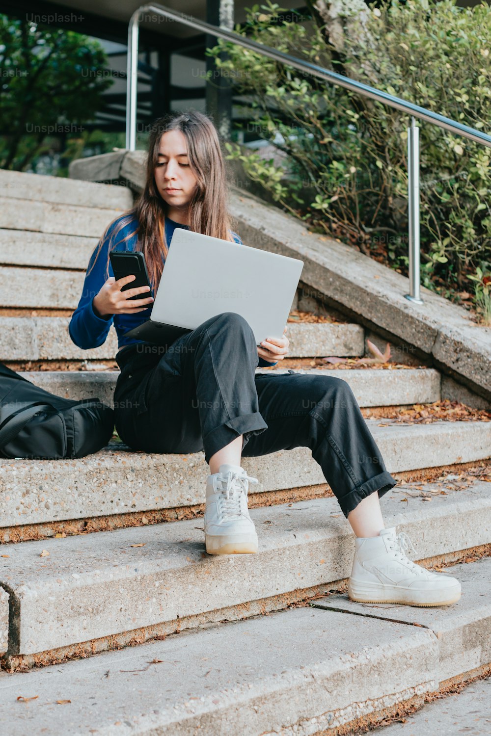 a woman sitting on steps using a laptop computer