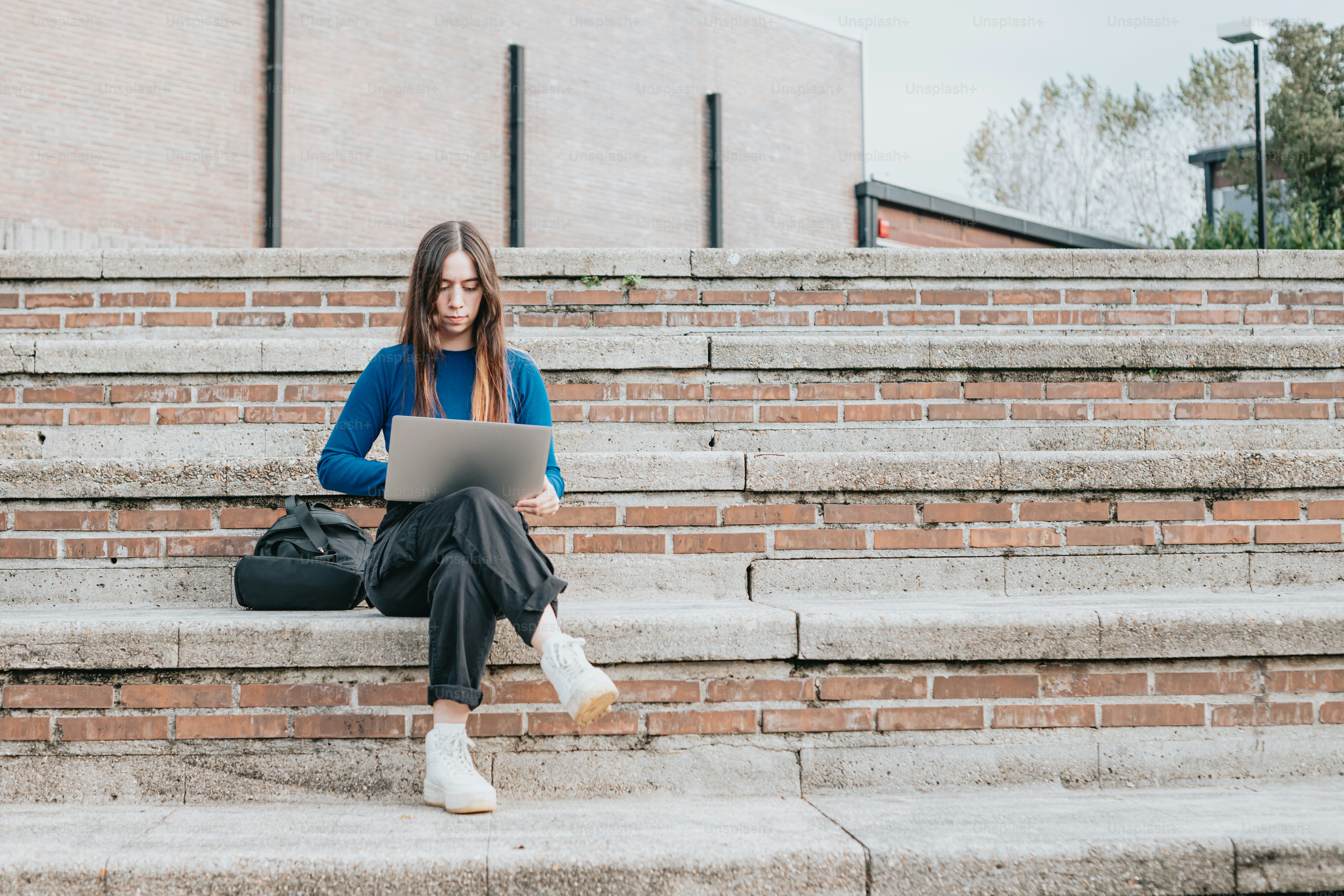 A woman sitting on steps using a laptop computer photo – Remote work ...