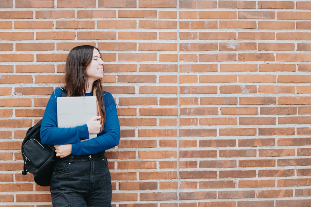 a woman standing in front of a brick wall