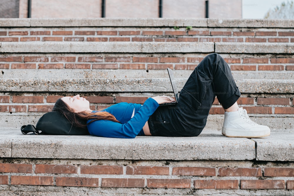 a woman laying on the steps with her laptop