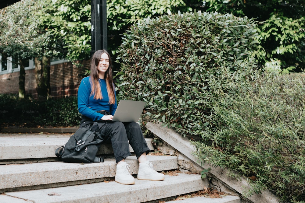 Una donna seduta sui gradini con un computer portatile