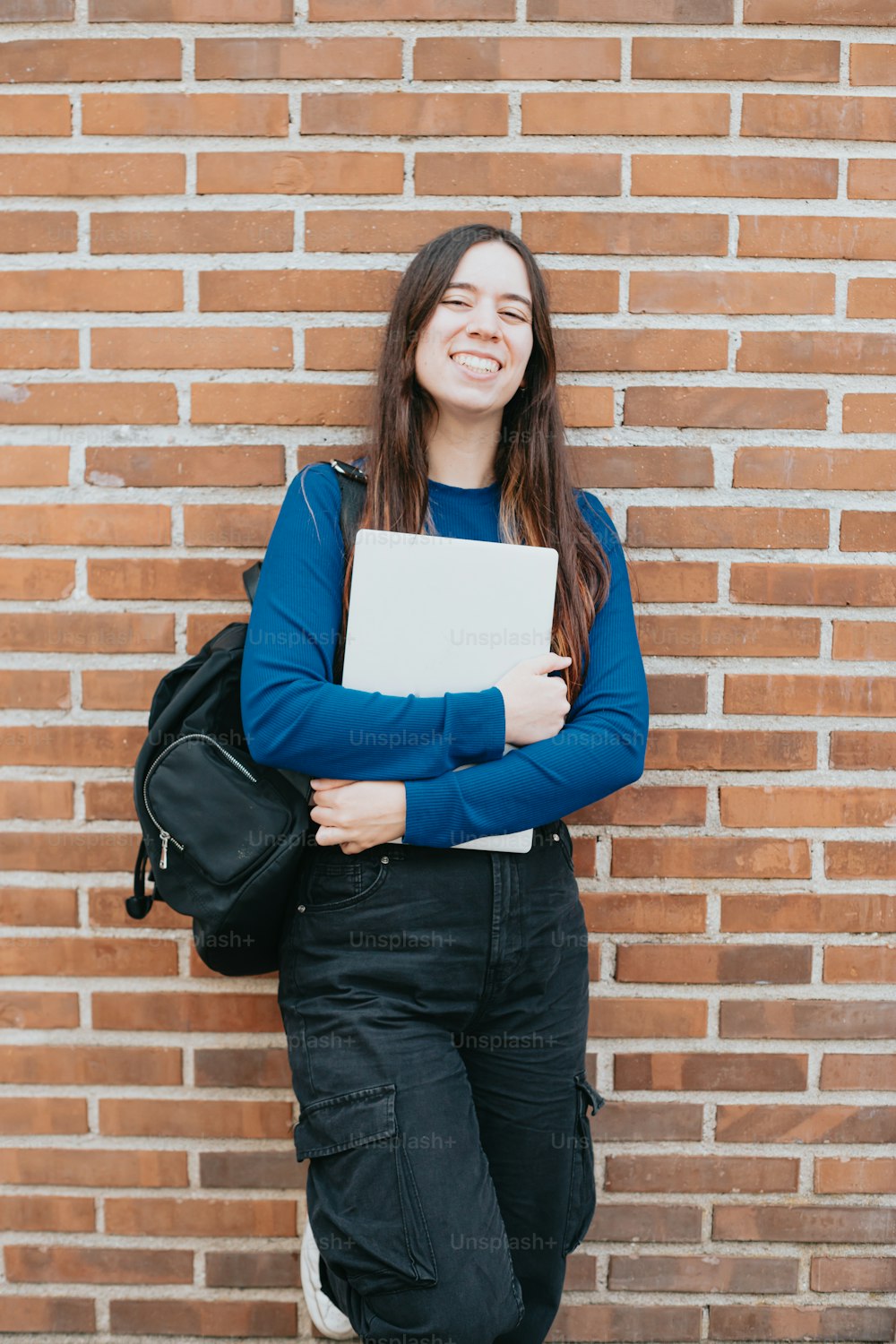 a woman standing in front of a brick wall