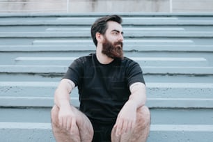 a man with a beard sitting on some steps
