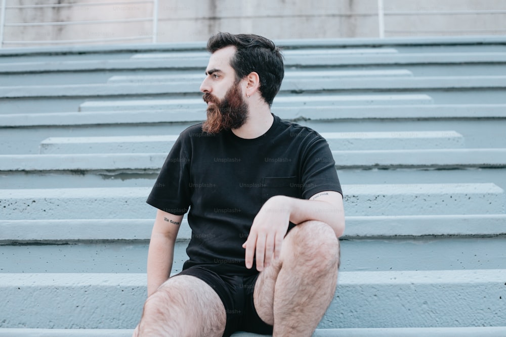 um homem com barba sentado em alguns degraus