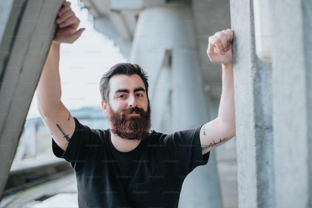 a man with a beard and tattoos holding onto a wall