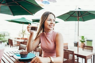 Junge Frau frühstückt mit Kaffee und Kuchen draußen in einem Café