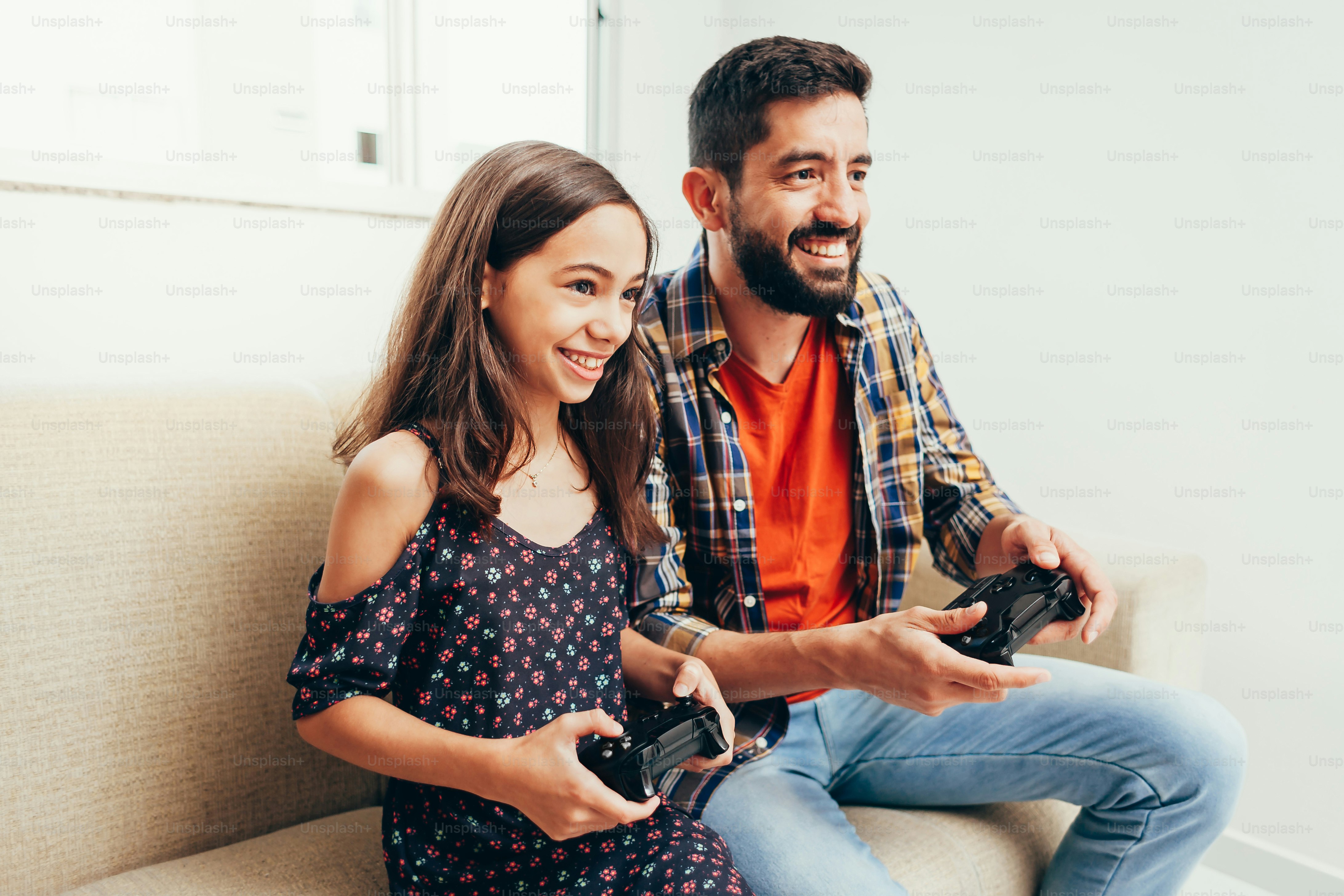 Smiling father and daughter playing video game at home