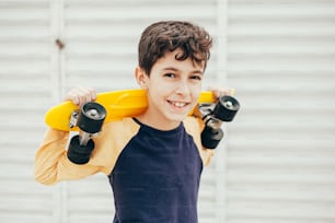 屋外でスケートボードを保持している9歳の少年の肖像画