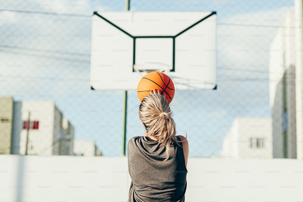 Mulher latina nova em sportswear jogando basquete na quadra ao ar livre