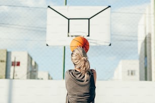 Joven mujer latina en ropa deportiva jugando baloncesto en cancha al aire libre