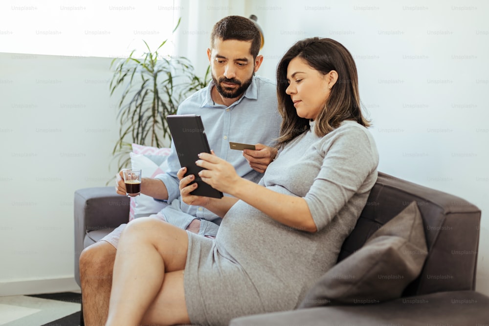 Adult couple expecting baby shopping online at home.
