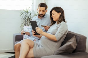 Couple adulte attendant bébé shopping en ligne à la maison.