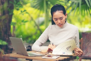 Uma atraente empresária de meia-idade sentada na frente do laptop e gerenciando seu pequeno negócio em casa.