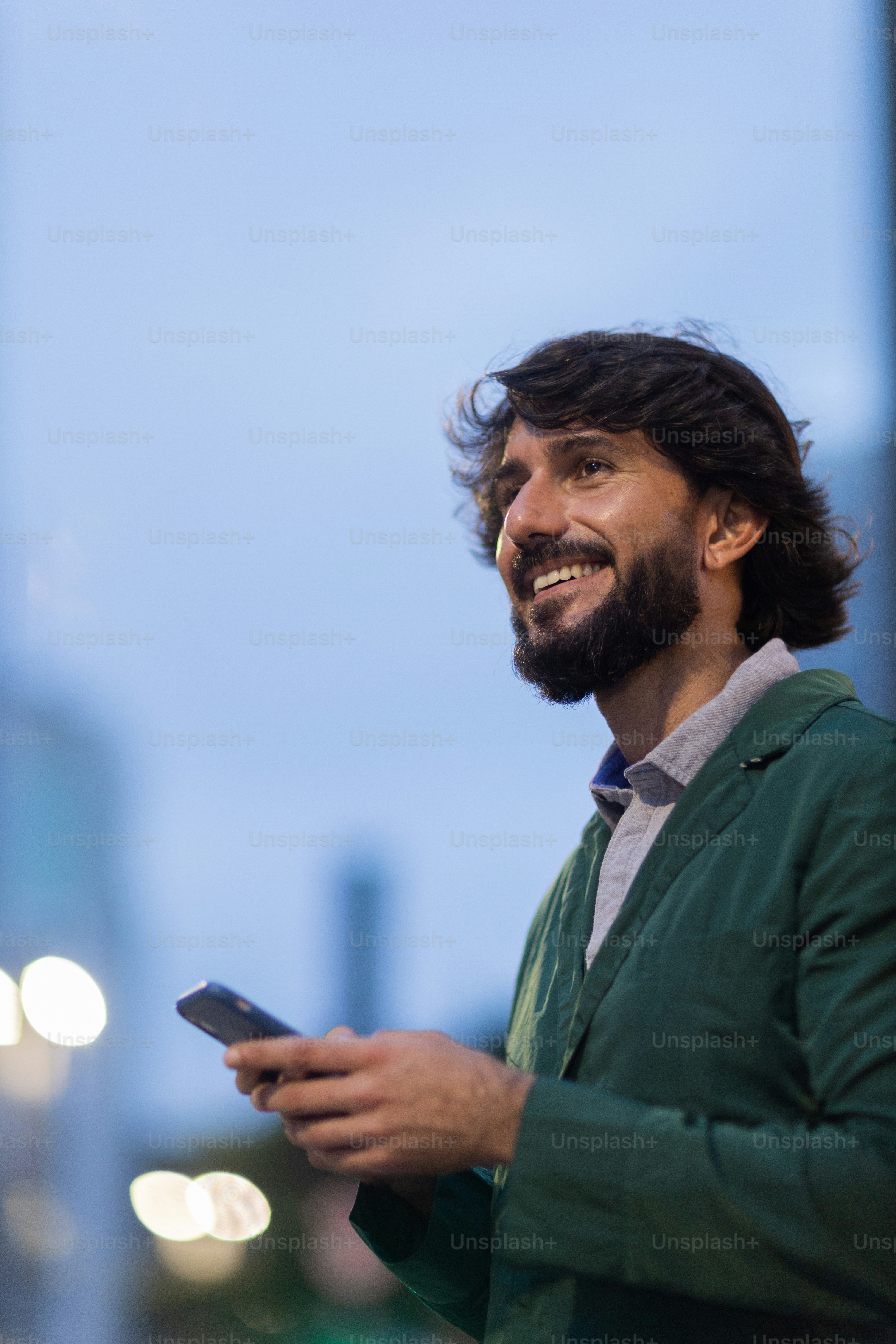 Vista del giovane che utilizza uno smartphone di notte con il paesaggio della vista della città sullo sfondo. Telefono cellulare, tecnologia, concetto urbano. Foto di alta qualità